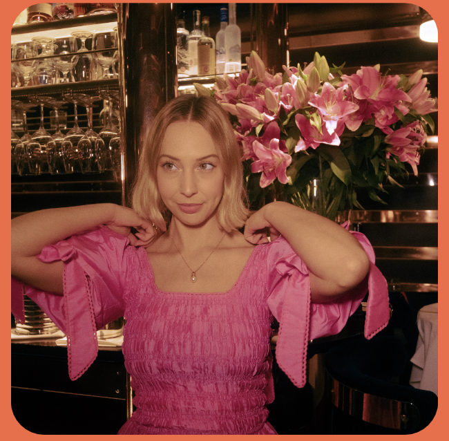Anastasia in a pink dress beside flowers